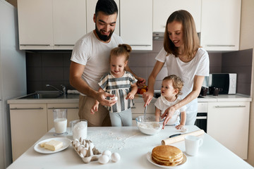 pleasant couple teaching their children to cook, family traditions. close up photo.