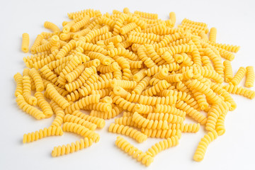 Dried fusili Italian pasta displayed randomly on a white table, ready to be cooked, isolated on table background, with top view