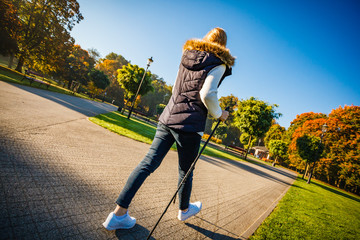 Nordic walking - middle-age woman working out in city park