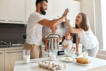 cheerful happy positive couple giving high five to each other, celebrating success while cooking in the kitchen. happiness, positive feeling and emotion