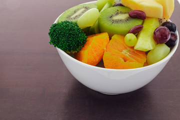 bowl of healthy fresh fruits salad on wooden background 