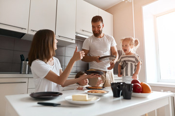 cheerufl mommy showing thumb up, expressing her happiness, she is praising her husband and kids for yummy pancakes, good jo, well done