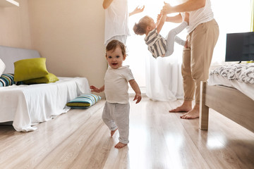 little nbaby walking in the bedroom while his daddy and mommy playing with elder sister. relationship concept