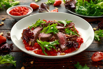 Beef Steak with Romesco sauce, nuts and vegetables on white plate