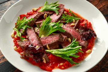 Beef Steak with Romesco sauce, nuts and vegetables on white plate