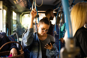 A young girl in glasses on a city bus. She holds the handle and talks on the phone © Razoran