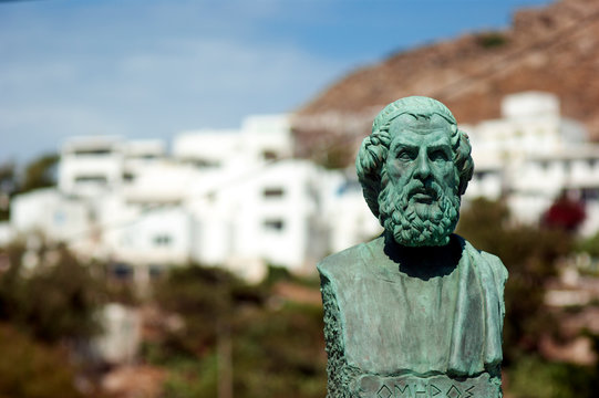 Greece, the island of Ios, the statue of Homer at the islands harbour. Blurred (bokeh) background, copy space.