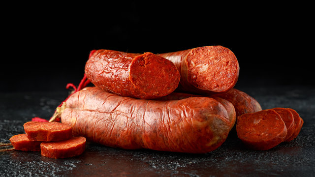 traditional Balearic raw cured meat sobrassada sausage made from ground pork, paprika and spices on rustic black background