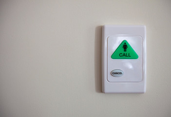 Green emergency call button on white wall.