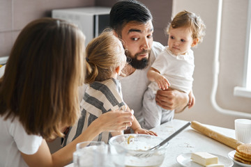 bearded funny man giving his cheek to his little daughter to kiss him. close up photo