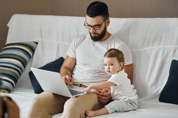 Obraz premium young handsome man and his baby typing somethiong on computer, having chat, conversation concept