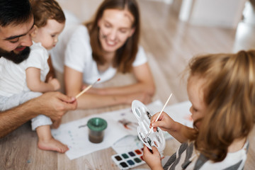 little adorable blonde girl holding pallet and mixing colours, close up cropped photo