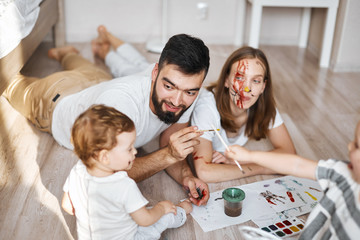 bearded man teaching his kid to hold a brush in hand, close up photo
