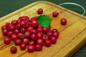 ripe red hawthorn berries on a kitchen board close-up
