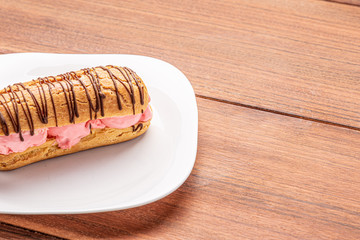 Profiteroles with ice cream and chocolate. Eclairs with black chocolate on wooden background. Traditional French dessert.