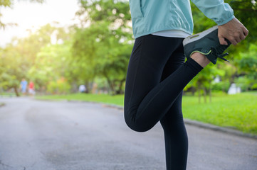 Young Healthy woman runner stretching legs before running in the park. Healthy workout woman jogging outdoors.