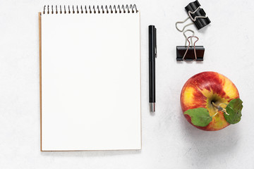 Back to school minimalism background with blank notepad, pen, binders and ripe juicy apple....