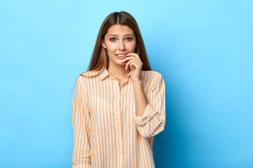 Worried frustrated woman looks nervously, bites finger nails, watches horror moving strilling film....