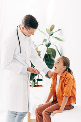 smiling pediatrist in white coat and child in clinic