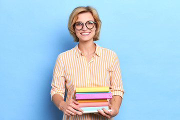 Nice cheerful teacher smiling and looking at camera holding colorful binders, close up portrait, paperwork, lifestyle, job, profession