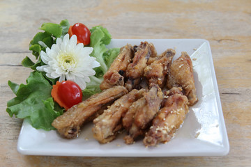 Fried chicken wings with sesame seeds on white plate.