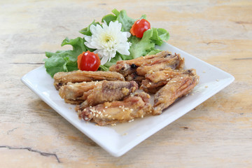 Fried chicken wings with sesame seeds on white plate.