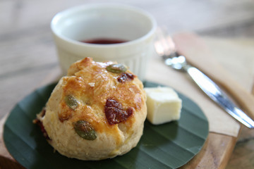 Delicious homemade muffin with butter on banana leaf on wooden tray.
