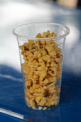 Pop corn in plastic clear glass on steel table.