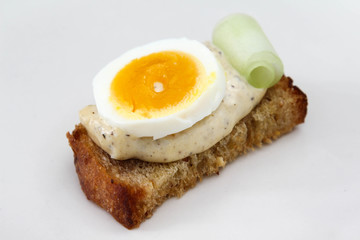 Sandwich with bread, salad dressing and boiled egg on white background.