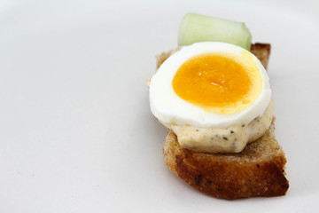 Sandwich with bread, salad dressing and boiled egg on white background.