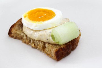 Sandwich with bread, salad dressing and boiled egg on white background.