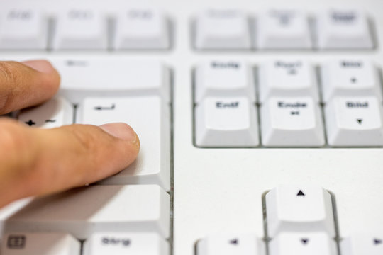 Finger auf dem Enter Button auf einer Tastatur
