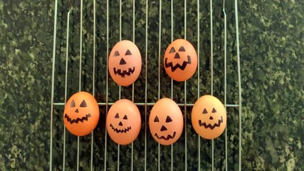 Halloween jack-o-lantern decorated hard boiled eggs bobbing on a rack