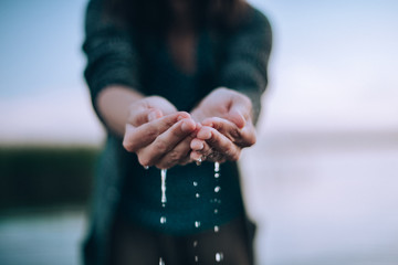 The girl holds water in the palms. Water dripping from the palms
