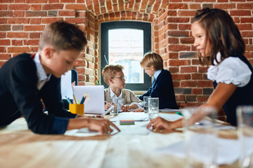 little boys discussing the problems of company, while a boy and a girl correcting mistakes of documents in the foreground of the photo, close up photo