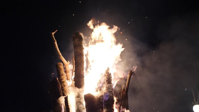 Fire flames and moke of big campfire go to dark night sky. Low angle shot