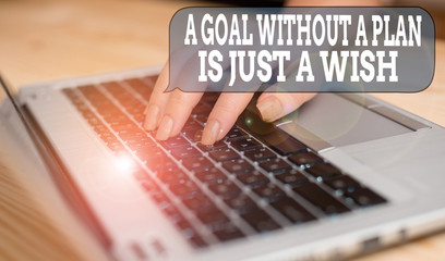 Writing note showing A Goal Without A Plan Is Just A Wish. Business concept for Make strategies to reach objectives woman with laptop smartphone and office supplies technology