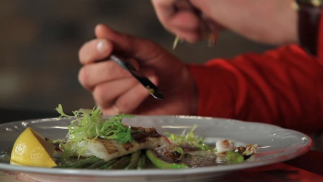 The process of eating blanched asparagus and grilled fillet of pike perch, served with lemon and herbs