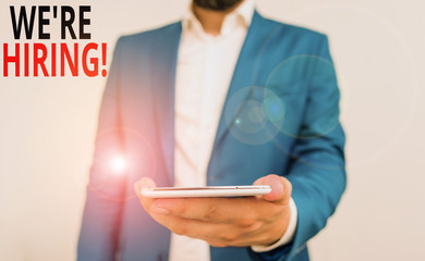 Word writing text We Re Hiring. Business photo showcasing recently employ someone or pay someone to do particular job Business concept with man holding mobile phone with touch screen