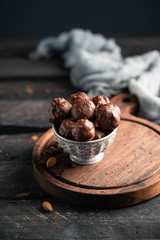 chocolates in a bowl, on a wooden board, on a dark wooden backdrop, healthy  snack