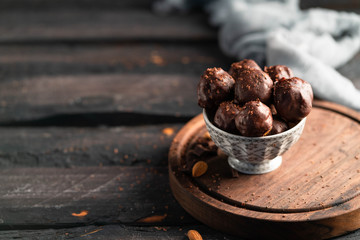 chocolates in a bowl, on a wooden board, on a dark wooden backdrop, healthy  snack