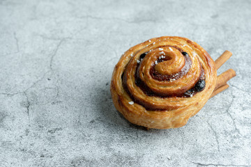 Sweet Cinnamon Roll, Swedish kanelbullar with sugar, on cement background.