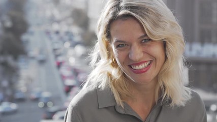 Charming mature happy woman laughing to the camera on urban background. Beautiful mid-aged female enjoying warm day, wandering at the city. Happiness, women concept