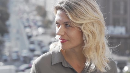 Beautiful mature woman smiling to the camera on city background. Attractive woman looking away thoughtfully, relaxing outdoors at the city. Lifestyle, confidence concept