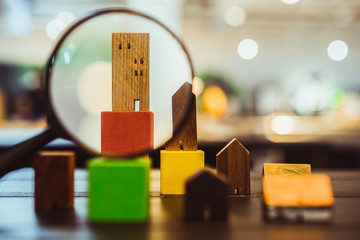 Hand holding magnifying glass and number of houses, house selection, house project, real estate...