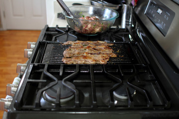 Korean style BBQ shortribs, known as Kalbi, on a cast iron grill in a home kitchen.