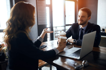 two cheerful business people having coffee break, enjoying drinking tea, pleasant conversation with a partner.