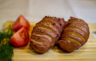 Potato accordion. Garnish potatoes stuffed with bacon and herbs on a wooden stand.
