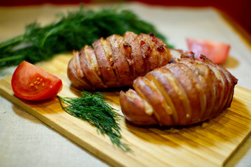 Potato accordion. Garnish potatoes stuffed with bacon and herbs on a wooden stand.