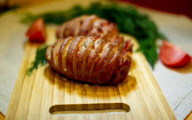 Potato accordion. Garnish potatoes stuffed with bacon and herbs on a wooden stand.